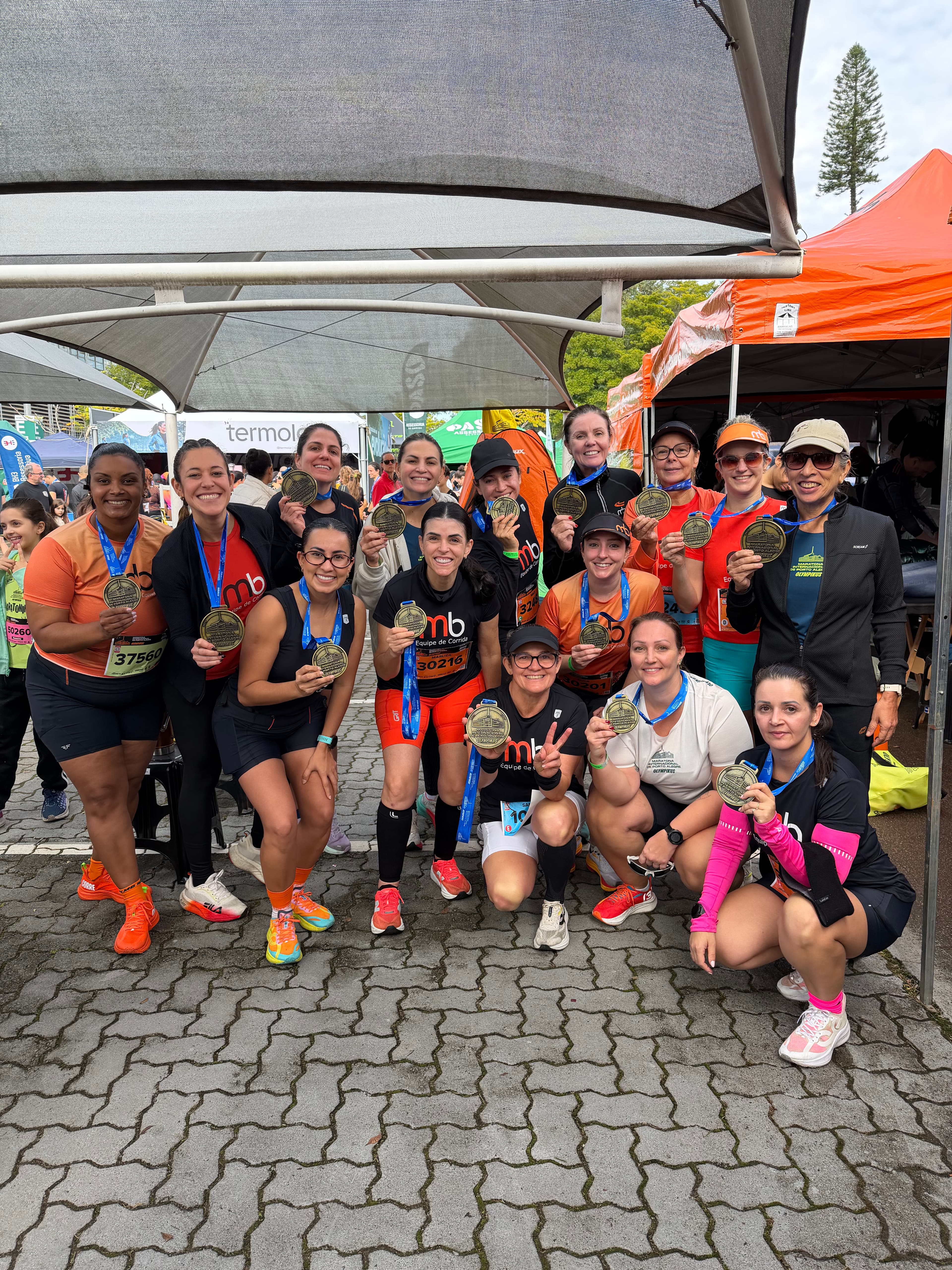 Atletas da equipe reunidas com as medalhas sob a tenda, ao fim da prova.