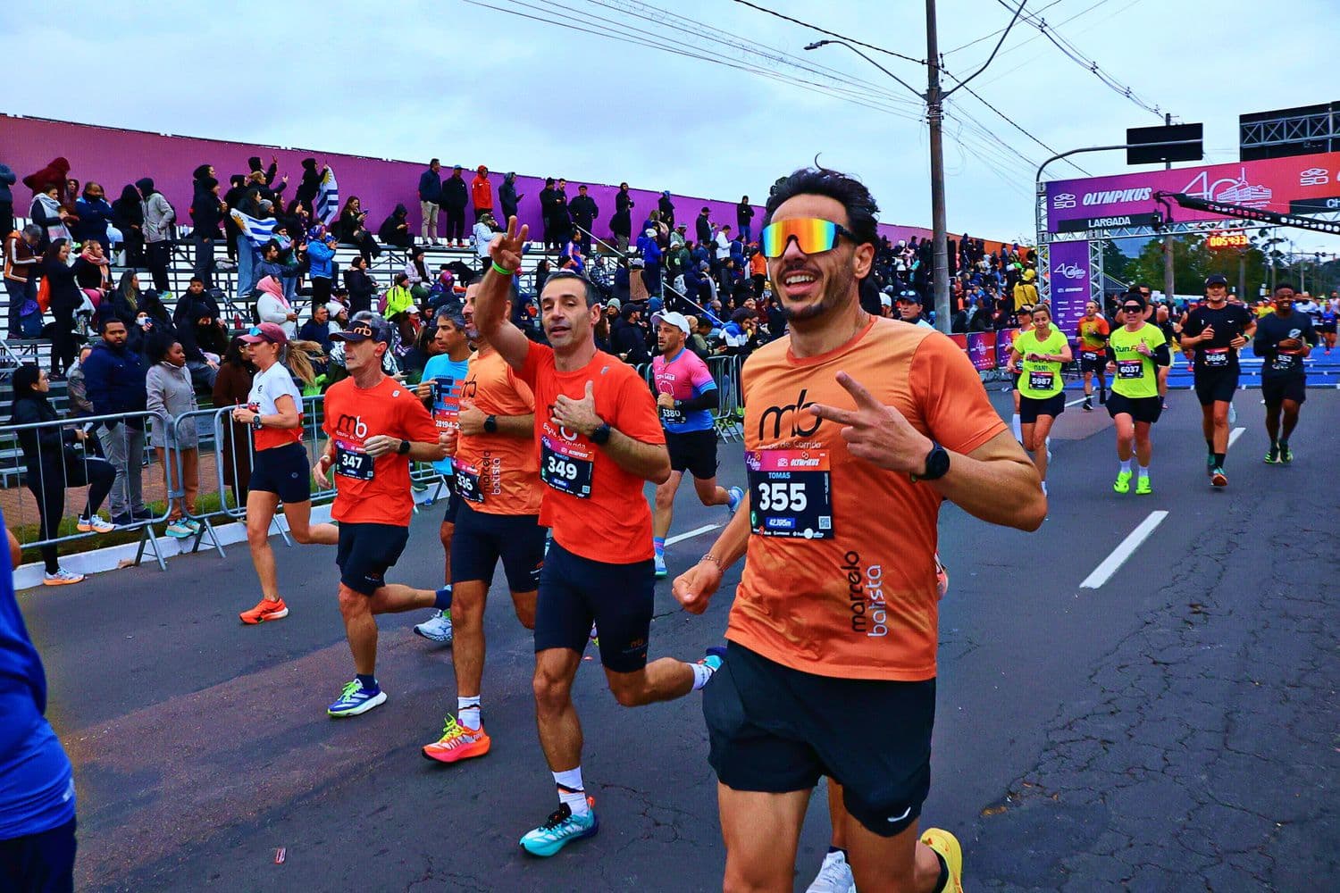 Atletas da equipe correndo em ritmo de prova diante da arquibancada.